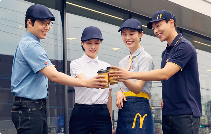 맥도날드 매장에서 직원들이 환하게 웃으며 손을 흔들면서 포즈를 취하고 있는 사진