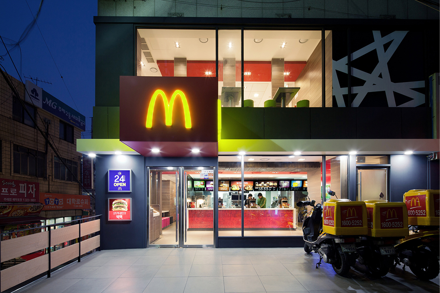 밤에 불이 켜진 맥도날드 매장 외관 전경으로 24시간 매장 오픈 서비스 안내