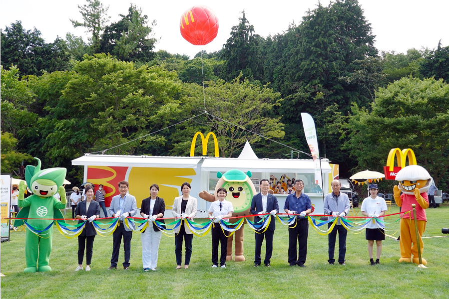 맥도날드 한국의 맛 프로젝트 일환으로 보성 녹돈 버거 페스티벌에서 귀여운 캐릭터와 관계자들이 야외 무대 앞에서 리본 커팅 기념식 모습